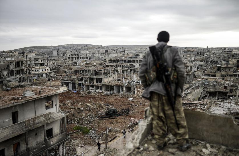 TOPSHOTS Musa, a 25-year-old Kurdish marksman, stands atop a building as he looks at the destroyed Syrian town of Kobane, also known as Ain al-Arab, on January 30, 2015. Kurdish forces recaptured the town on the Turkish frontier on January 26, in a symbolic blow to the jihadists who have seized large swathes of territory in their onslaught across Syria and Iraq. AFP PHOTO/BULENT KILICBULENT KILIC/AFP/Getty Images