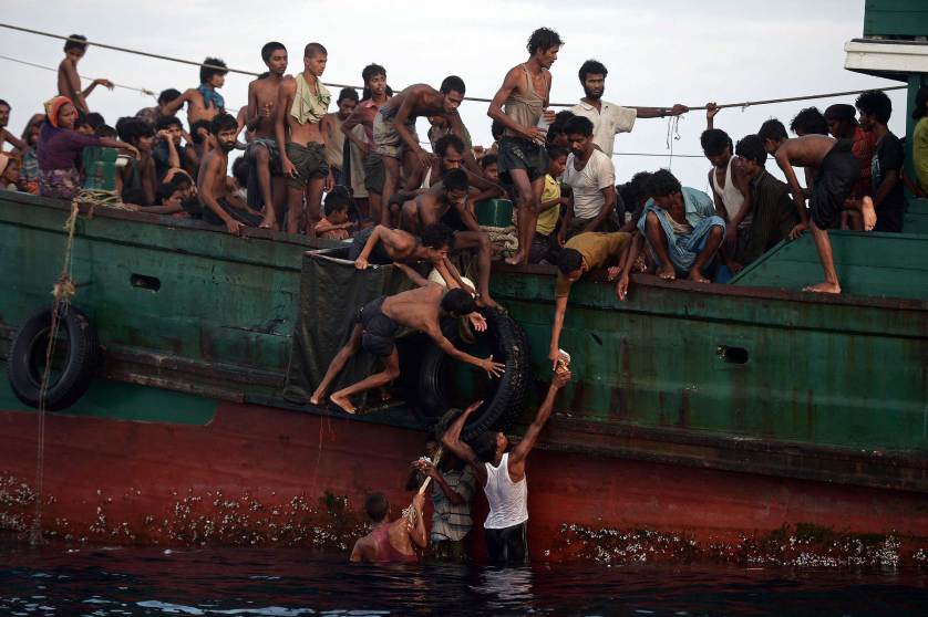 TOPSHOTS Rohingya migrants pass food supplies dropped by a Thai army helicopter to others aboard a boat drifting in Thai waters off the southern island of Koh Lipe in the Andaman sea on May 14, 2015. A boat crammed with scores of Rohingya migrants -- including many young children -- was found drifting in Thai waters on May 14, with passengers saying several people had died over the last few days. AFP PHOTO / Christophe ARCHAMBAULTCHRISTOPHE ARCHAMBAULT/AFP/Getty Images