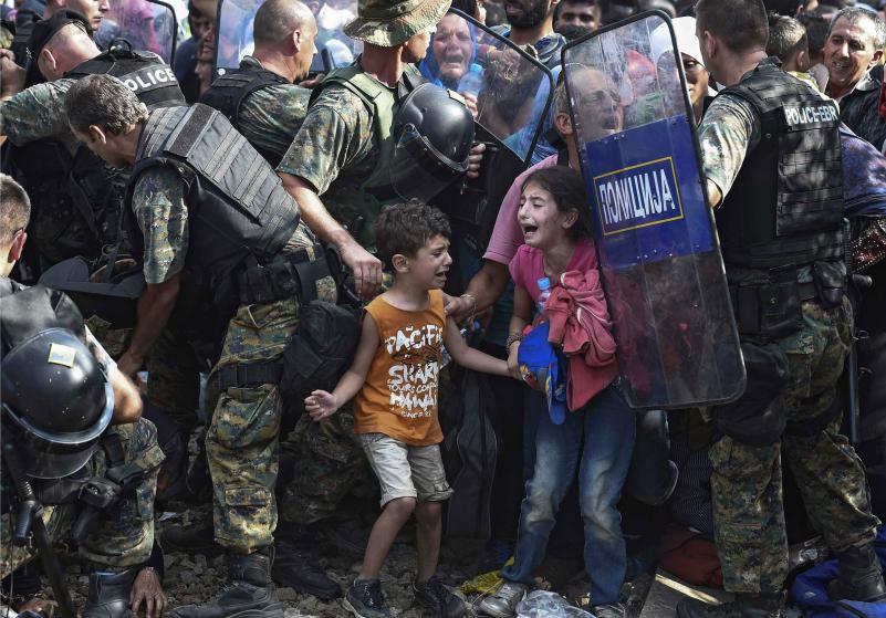 epaselect epa04891691 Children cry as migrants waiting on the Greek side of the border break through a cordon of Macedonian special police forces to cross into Macedonia, near the southern city of Gevgelija, The Former Yugoslav Republic of Macedonia, 21 August 2015. Macedonian police clashed with thousands of migrants attempting to break into the country after being stranded in no-man's land overnight, marking an escalation of the European refugee crisis for the Balkan country. EPA/GEORGI LICOVSKI