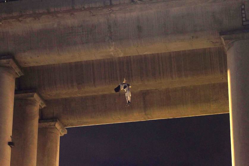 An unidentified dead man hangs from his waist under an overpass in the southern part of Mexico City, early Monday, Oct. 19, 2015. The man was found wrapped in white bandages and a cap, or hoodie, was covering his head. This is the first time a body appears on a bridge or overpass in Mexico City, a common practice among criminal gangs fighting for control of turf in other regions of Mexico. Mexico City authorities have repeatedly stated that the capital is safe from the wave of violence that continues to affect many parts of the country. (AP Photo/Jair Cabrera)