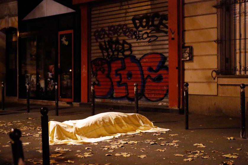 A victim under a blanket lays dead outside the Bataclan theater in Paris, Friday Nov. 13, 2015. Well over 100 people were killed in a series of shooting and explosions explosions. French President Francois Hollande declared a state of emergency and announced that he was closing the country's borders. (AP Photo/Jerome Delay)