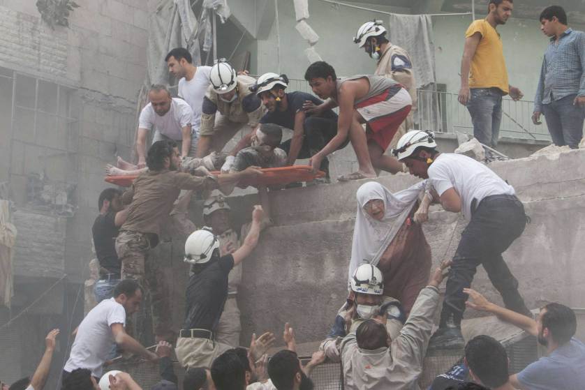 TOPSHOTS Syrian rescue workers and citizens evacuate people from a building following a reported barrel bomb attack by Syrian government forces on the central al-Fardous rebel held neighbourhood of the northern Syrian city of Aleppo, on June 9, 2015. AFP PHOTO / KARAM AL-MASRI KARAM AL-MASRI/AFP/Getty Images