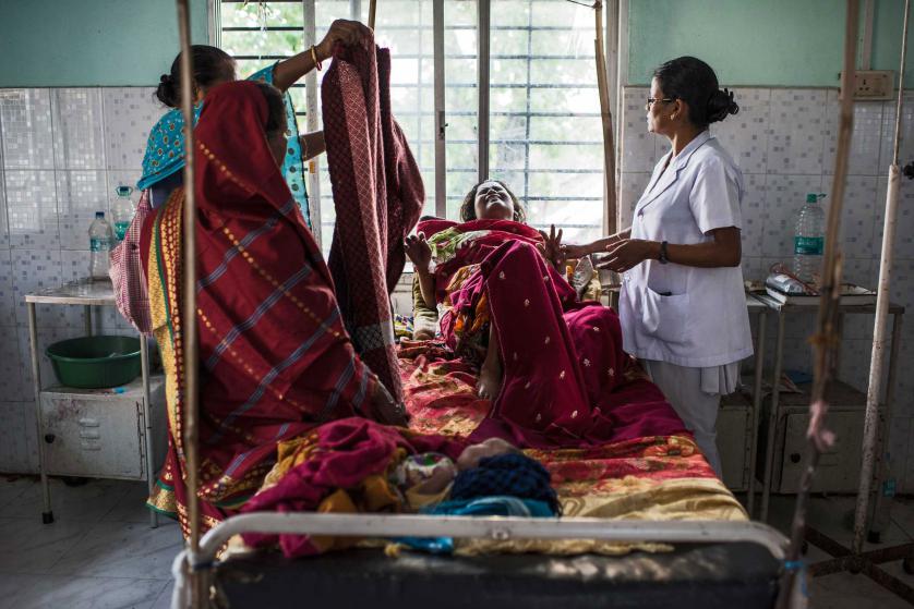 Nazreen Khatoon winces in pain as she is repositioned by a nurse as she lies gravely ill while suffering from severe postpartum anemia at the Tezpur Civil Hospital in Tezpur, Assam, India, April 2015. Khatoon delivered her son, Kashari Pam, roughly three weeks prior, and returned to the hospital about two weeks after delivery when her condition worsened. When we met her, she was in dire need of both blood and iron, and was not receiving either from the Tezpur Hospital; she was eventually referred to a private hospital, where she was able to receive better care, but at a great expense to the family. Many of Assam's state-run medical facilities are often overcrowded and unhygenic, with an insufficient number of doctors, and patients sprawled out in the floors and hallways due to a limited number of beds. Assam has the highest rate of women dying in chidbirth and from pregnancy-related causes in all of india, where roughly 50,000 women die annually in childbirth across the country. Many families in Assam work on the tea plantations, where there is a high rate of pregnant and lactating women who are severely anemic due to poor diets and little to no prenatal care, leading to a high number of pregnancy complications. (Credit: Lynsey Addario/ Getty Images reportage for Every Mother Counts)