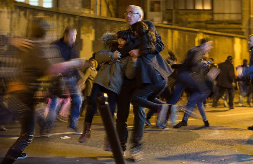 A man carries two children after panic broke out among mourners who payed their respect at the attack sites at restaurant Le Petit Cambodge (Little Cambodia) and the Carillon Hotel in Paris, Sunday, Nov. 15, 2015. Thousands of French troops deployed around Paris on Sunday and tourist sites stood shuttered in one of the most visited cities on Earth while investigators questioned the relatives of a suspected suicide bomber involved in the country's deadliest violence since World War II. (AP Photo/Peter Dejong)