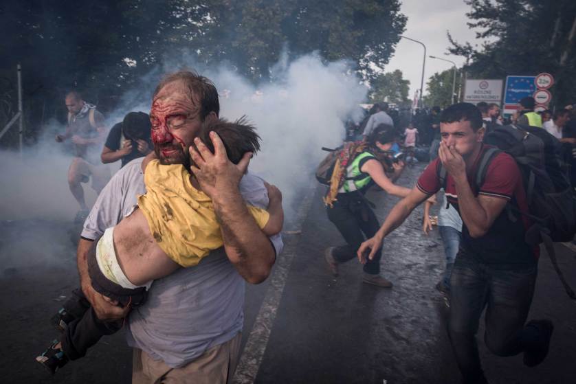A migrant holds his child during a clash with Hungarian riot police at the Horgos border crossing in Serbia, Sept. 16, 2015. Hundreds of migrants remained stranded on Serbia?s border with Hungary early Wednesday as Hungary?s decision to seal its border rippled across Europe and other migrants scrambled to find alternative routes, in an effort, in most cases, to reach Germany. (Sergey Ponomarev/The New York Times)