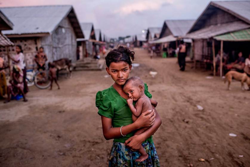Oma Salema, 12, holds her undernourished brother Ayub Khan, 1, at a camp for Rohingya in Sittwe, Myanmar, June 5, 2015. The government of Myanmar says it is determined to stop the departures of migrants fleeing religious persecution in places like Sittwe, but it will not budge in its refusal to address the conditions driving the exodus across the sea. (Tomas Munita/The New York Times)
