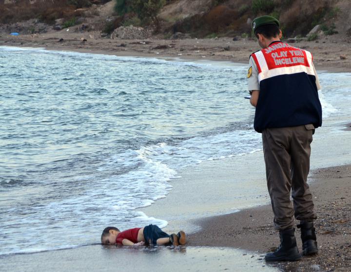 FILE - In this Sept. 2, 2015 file photo, a paramilitary police officer investigates the scene before carrying the lifeless body of Aylan Kurdi, 3, after a number of migrants died and others were reported missing when boats carrying them to the Greek island of Kos capsized near the Turkish resort of Bodrum. The tides also washed up the bodies of the boy's 5-year-old brother Ghalib and their mother Rehan on Turkey's Bodrum peninsula. Their father, Abdullah, survived the tragedy. (AP Photo/DHA, File) TURKEY OUT