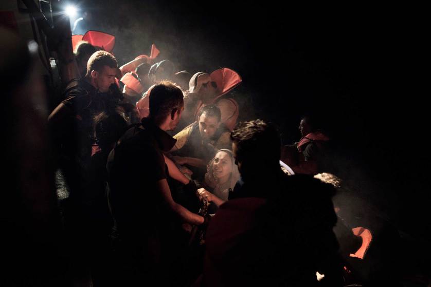 Syrian migrants scramble aboard a Greek coast guard vessel from the rubber motorboat they were using to cross from Turkey to the Greek islands. The coast guards have orders to rescue any migrant boats they find during night patrols of the Aegean Sea and bring them to Greece for processing and registration. Sept. 7, 2015.